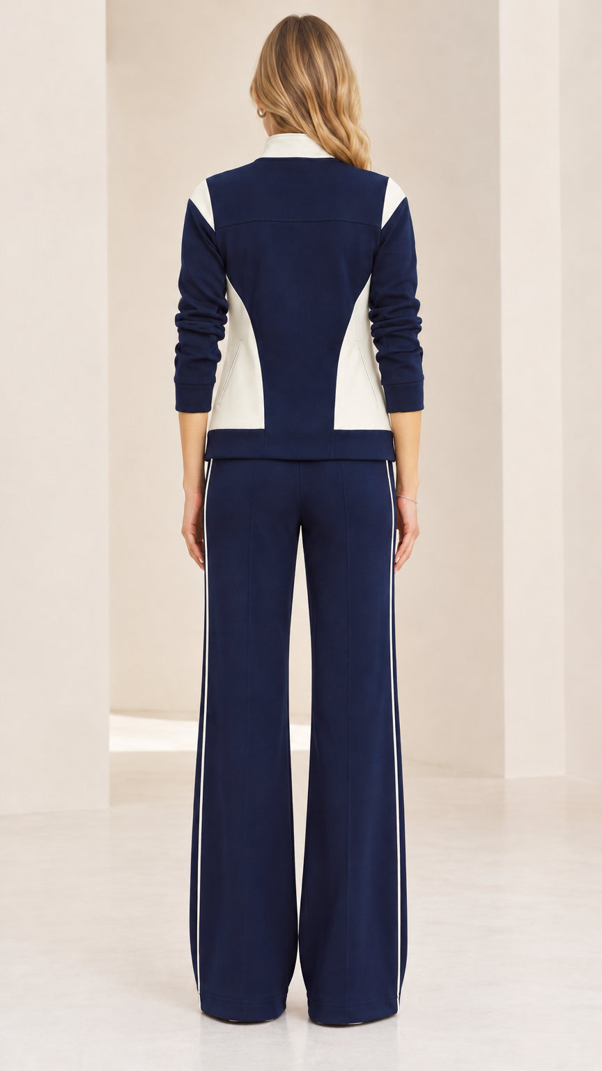 Back view of woman wearing navy blue colorblock jacket and wide-leg track pants