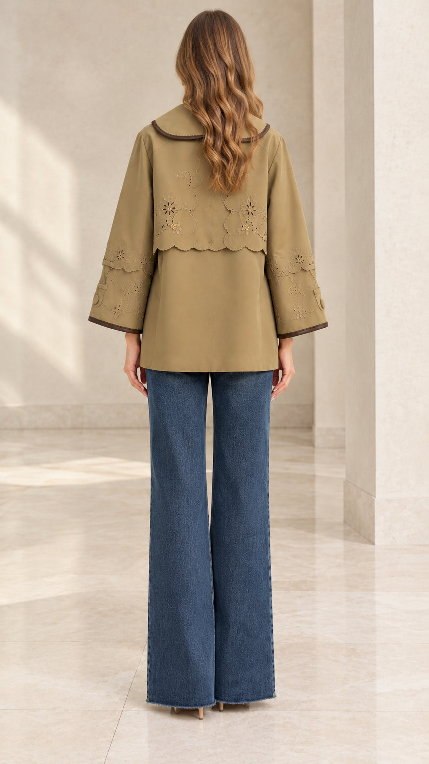 Back full-length view of woman wearing khaki embroidered capelet jacket with scalloped overlay