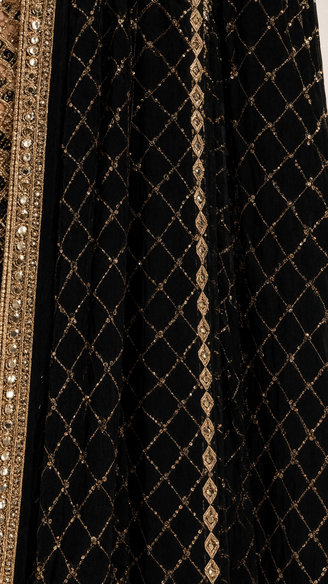 Close-up detail of geometric gold sequin lattice embroidery and ornate border on black fabric