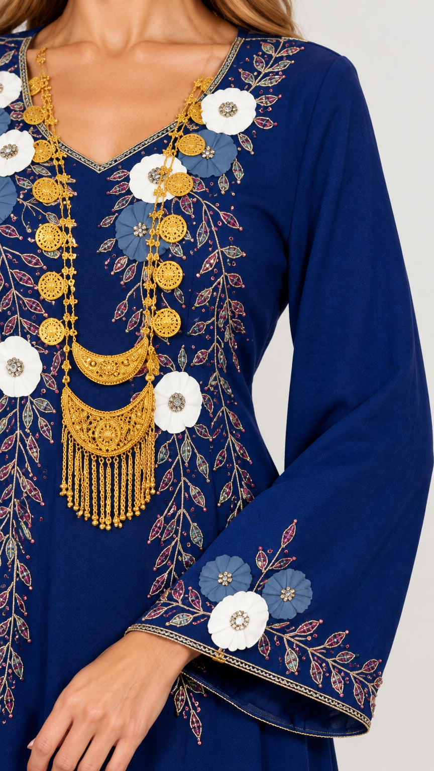 Close-up detail of ornate botanical embroidery and golden neckline accents on royal blue fabric