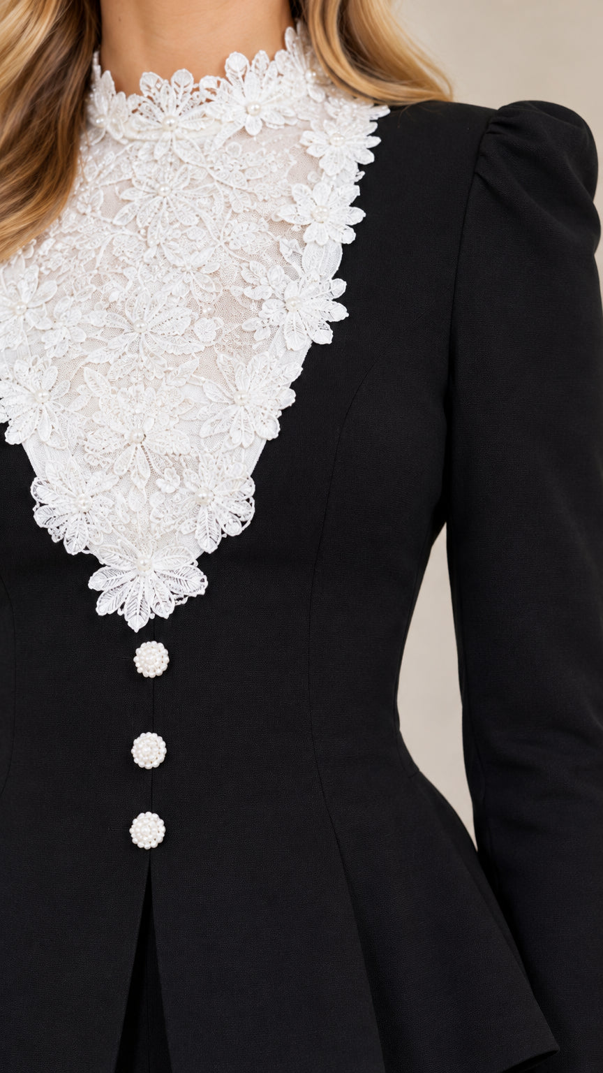 Close-up detail of white floral lace bib neckline and button accents on black peplum jacket