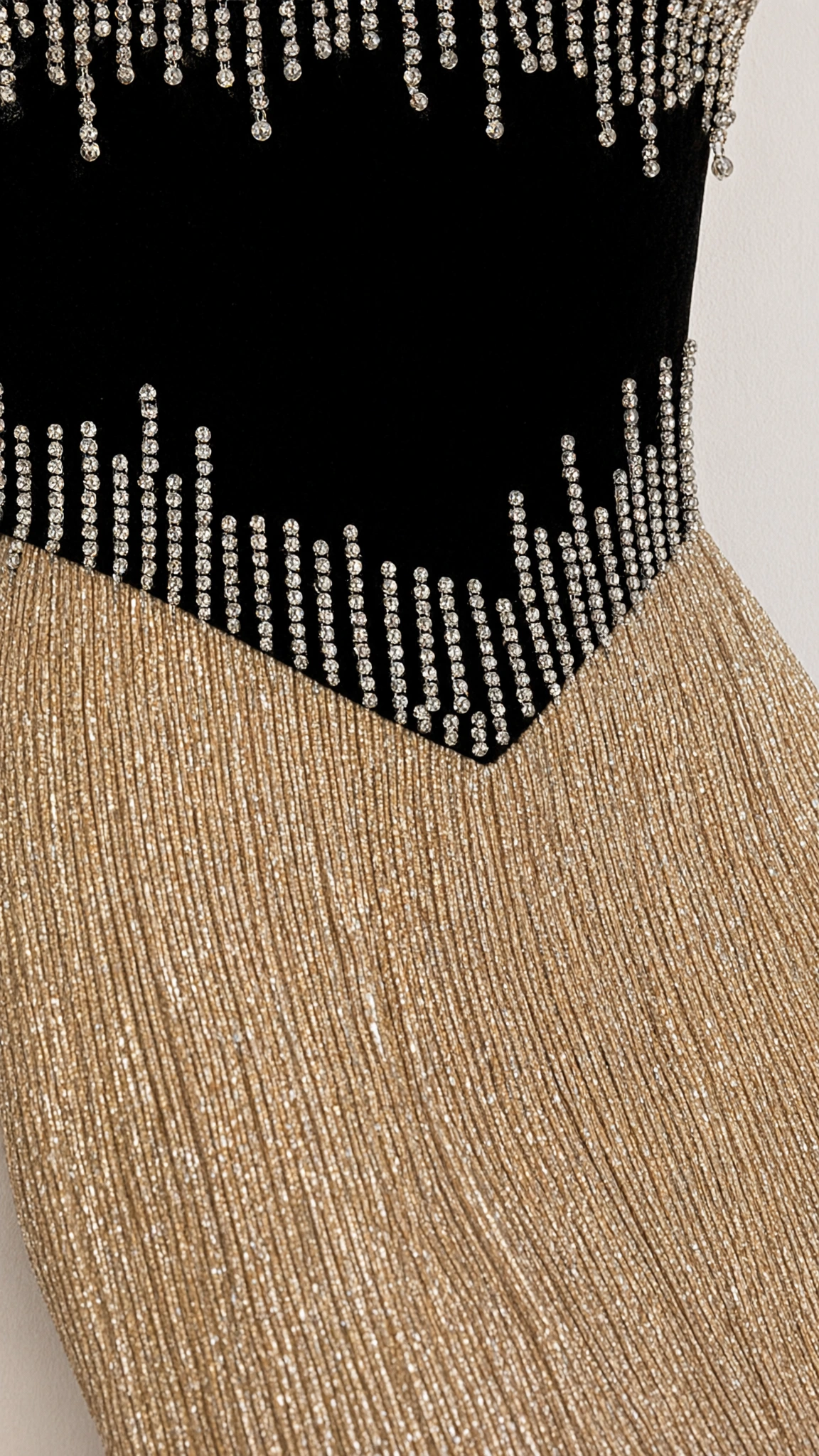 Close-up detail of rhinestone embellishments on contrast black waist panel and gold glitter fabric