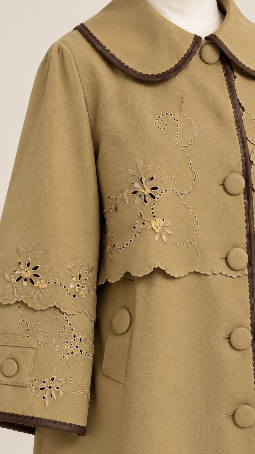 Close-up detail of khaki jacket featuring delicate floral cutwork embroidery and Peter Pan collar