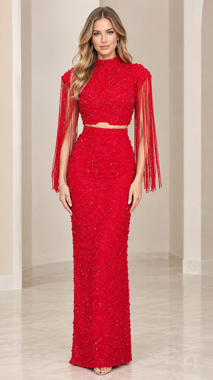 Front full-length view of model wearing red beaded two-piece mock neck evening gown with shoulder fringe
