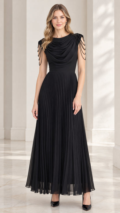 Front view of model wearing black cowl neck pleated maxi evening dress with beaded shoulder fringe