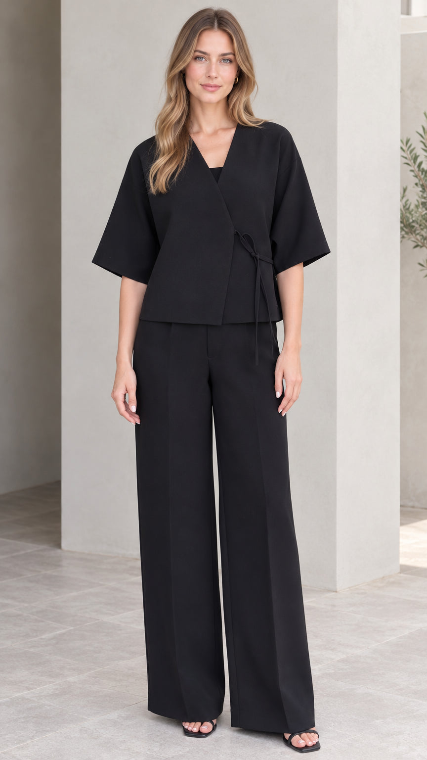 Front full-length view of model wearing black wrap top and wide-leg trousers set