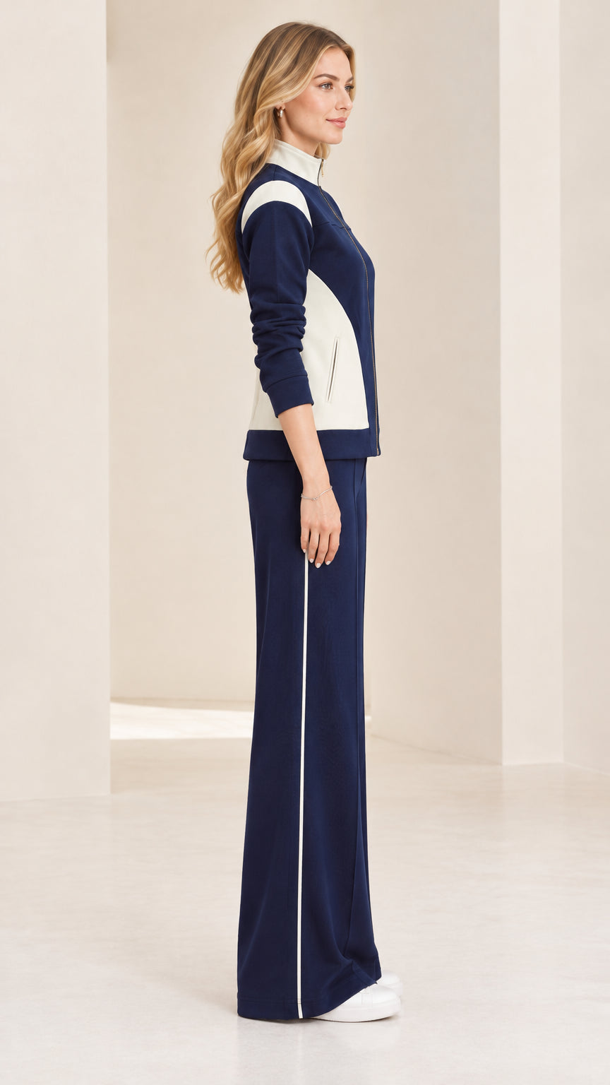 Side profile view of woman wearing navy blue tracksuit set with side stripe detail
