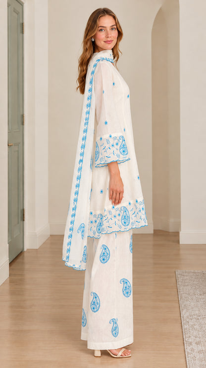 Side profile view of model in white embroidered 3-piece set with draped scarf