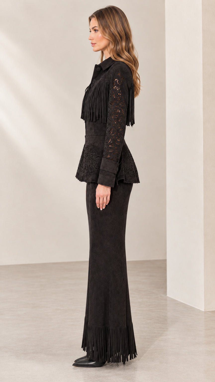 Side view of model wearing black western fringe peplum jacket and maxi skirt