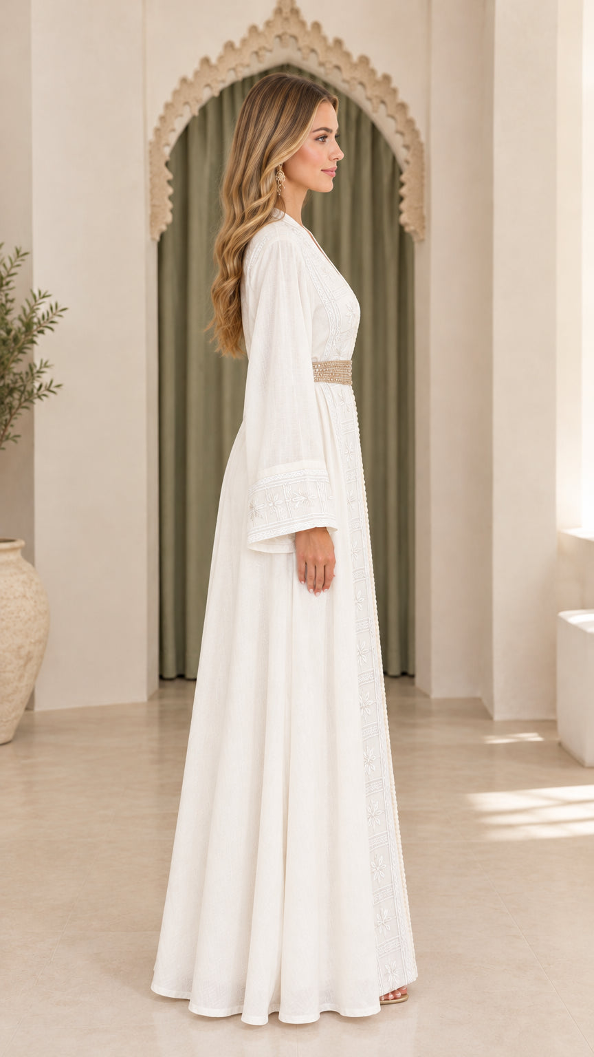 Side profile view of woman in flowing white embroidered maxi dress