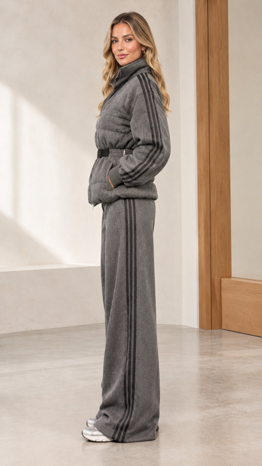 Side profile view of woman wearing grey quilted jacket and side-striped wide-leg pants