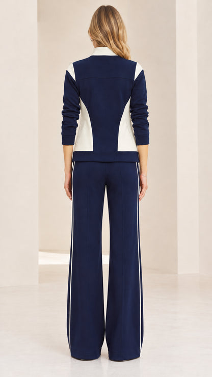 Back view of woman wearing navy blue colorblock jacket and wide-leg track pants