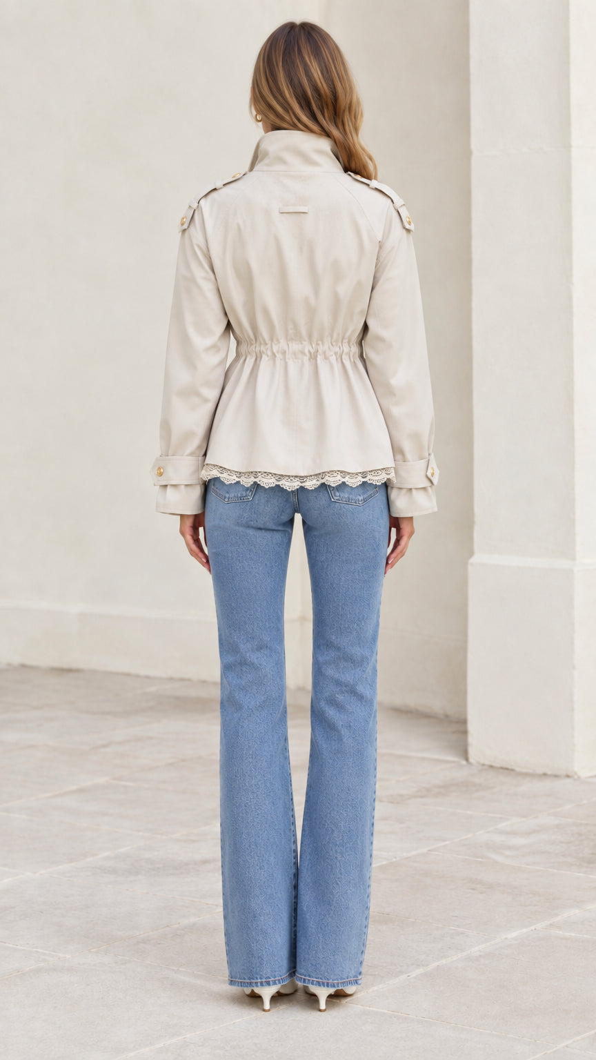 Back view of model wearing beige utility jacket highlighting elastic gathered waistline