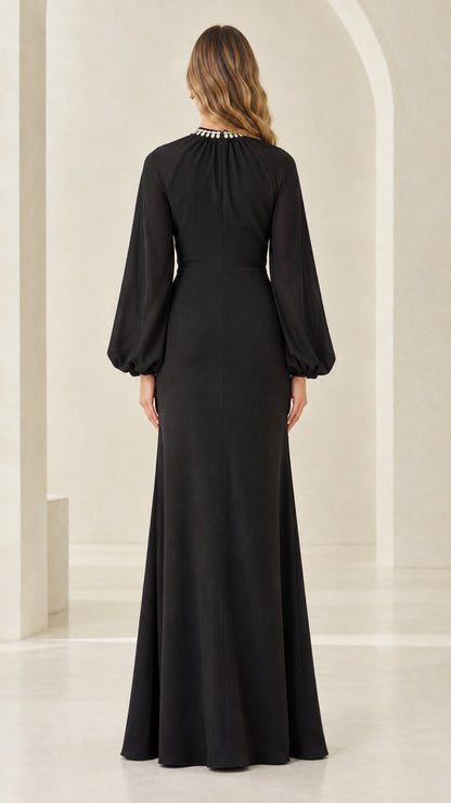 Back full-length view of woman in black cape sleeve evening maxi dress