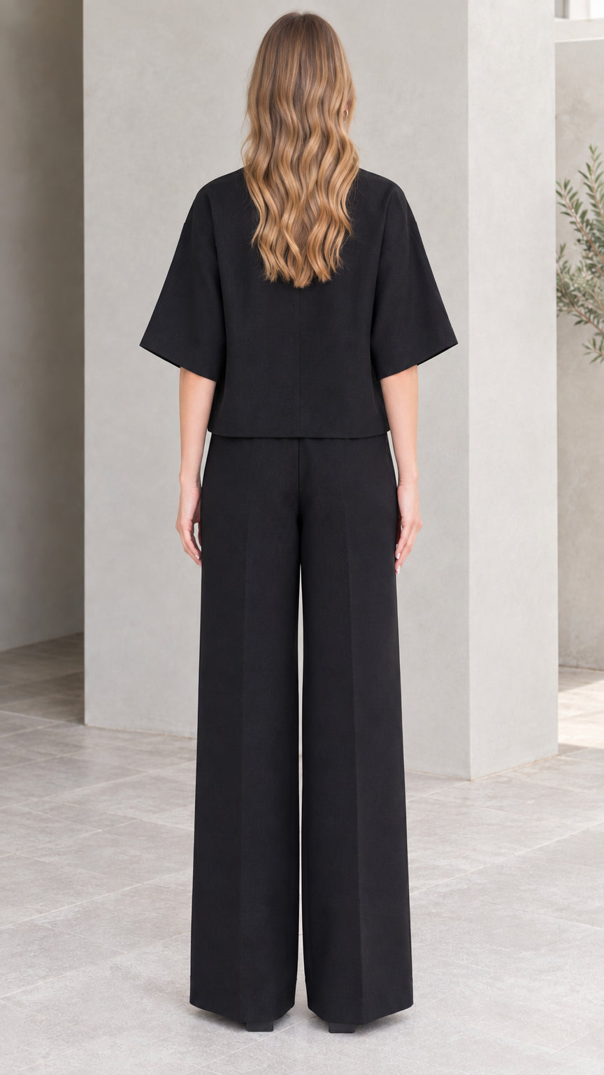Back full-length view of black wide sleeve wrap top and wide-leg trousers