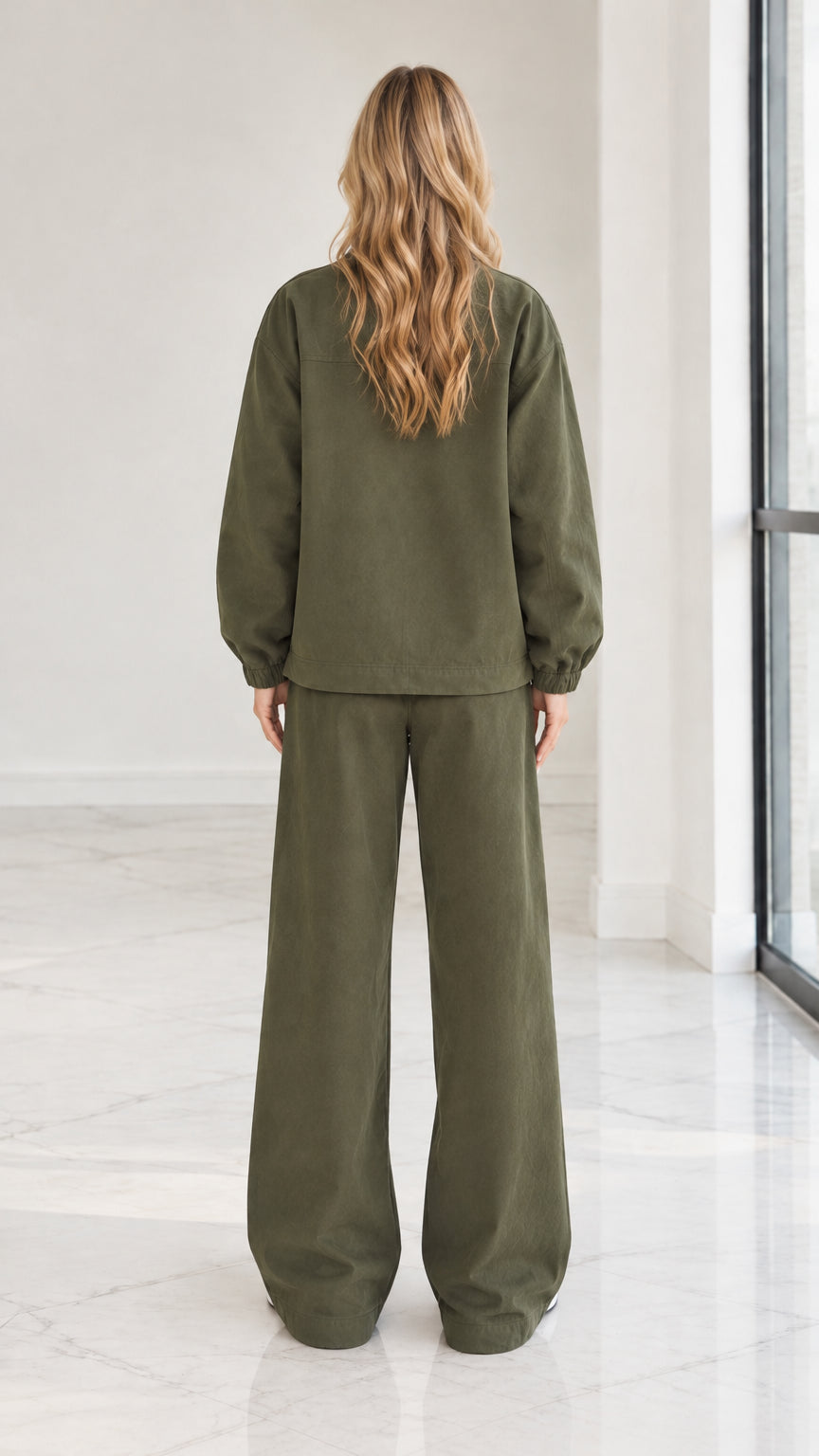 Back full view of woman wearing olive green 2-piece zip jacket and wide leg pants set