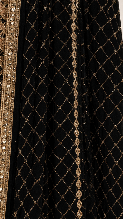 Close-up detail of geometric gold sequin lattice embroidery and ornate border on black fabric