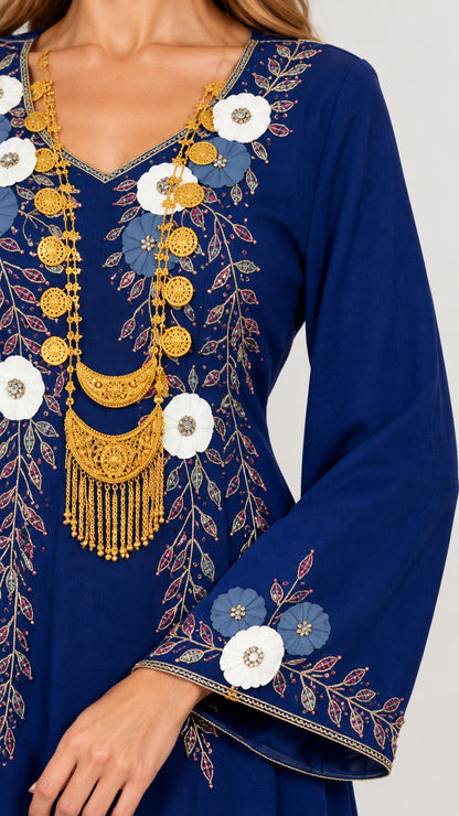 Close-up detail of ornate botanical embroidery and golden neckline accents on royal blue fabric