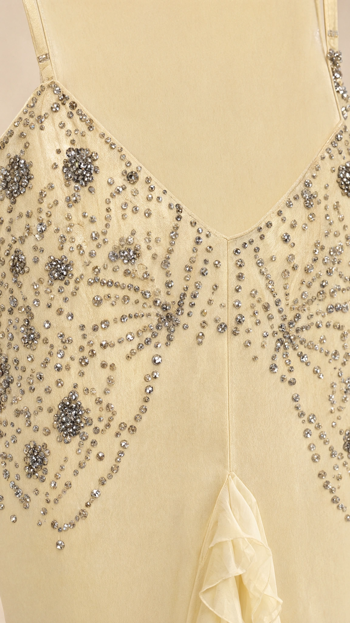 Close-up detail of delicate rhinestone and bead embellishments on yellow fabric