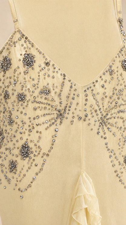 Close-up detail of delicate rhinestone and bead embellishments on yellow fabric