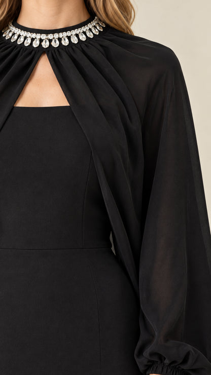 Close-up detail of rhinestone embellished collar and sheer cape on black evening gown