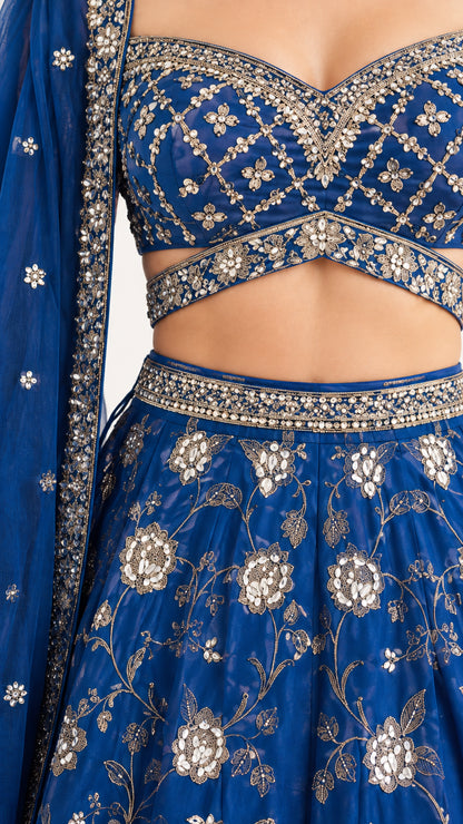 Close-up detail of metallic floral embroidery on royal blue crop top and waistband