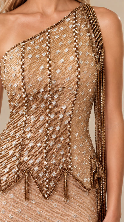 Close-up detail of crystal beadwork and shoulder tassel on champagne evening gown
