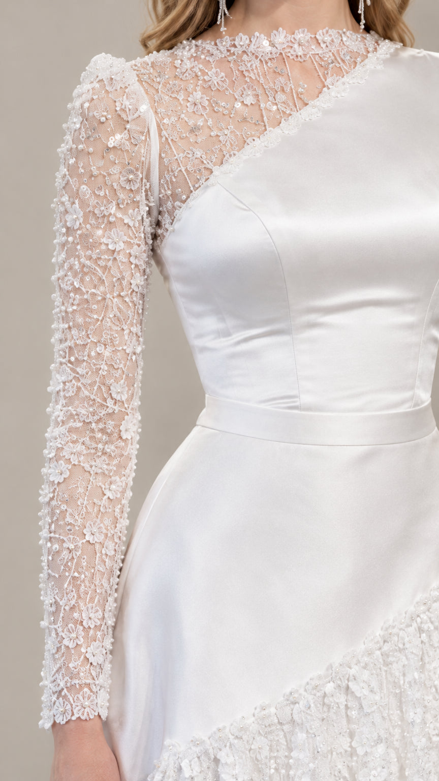 Close-up detail of sheer beaded lace sleeve and satin bodice on white gown