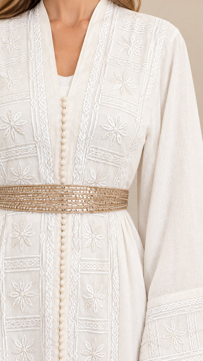 Close-up detail of floral embroidery and metallic belt on white abaya dress