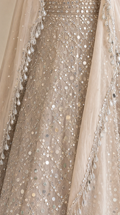 Close-up detail of mirror embellishments and fringe trims on champagne evening gown