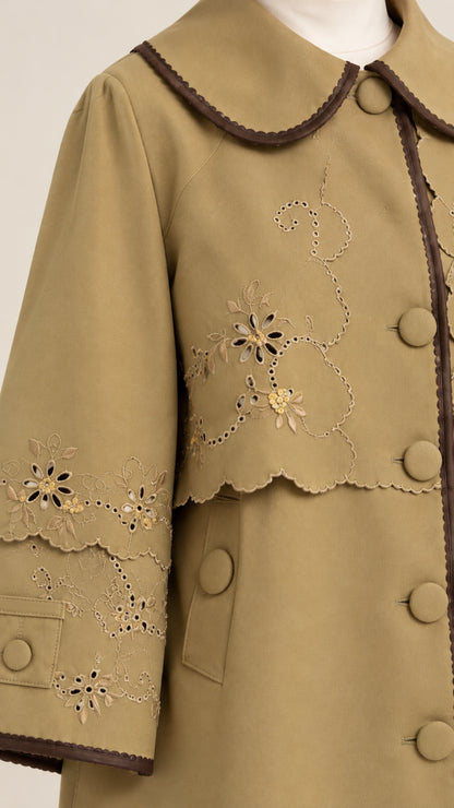Close-up detail of khaki jacket featuring delicate floral cutwork embroidery and Peter Pan collar