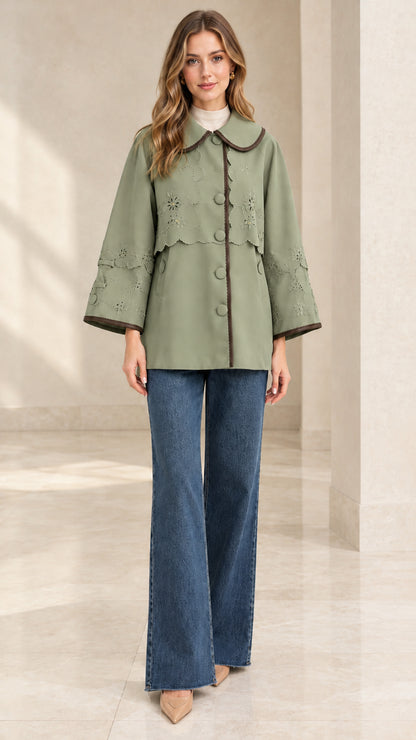 Full-length front view of woman wearing sage green embroidered scalloped capelet jacket