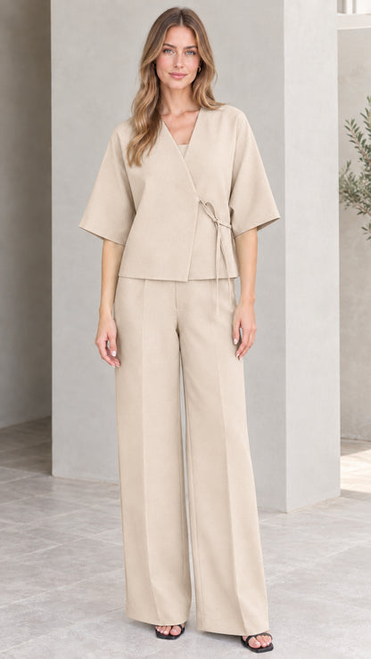 Full-length view of model wearing beige cream wrap top and tailored trousers set